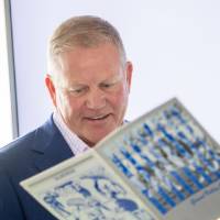 Brian Kelly looking at a book with a guest at the Jamie Hosford Football Center dedication.